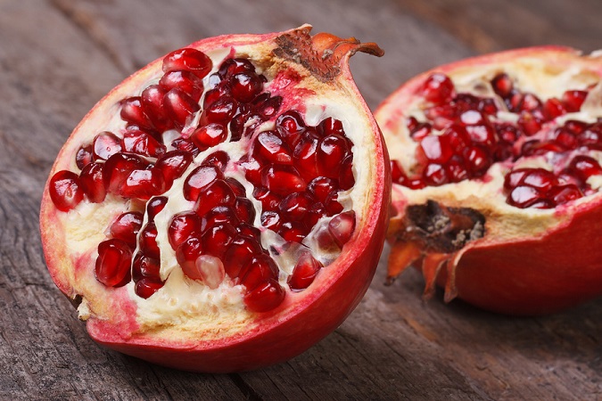 Cut Ripe Pomegranate On An Old Wooden Table. Horizontally