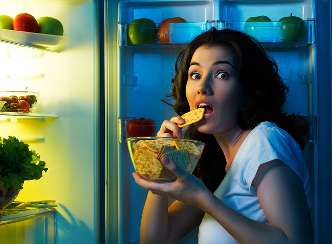 a hungry girl opens the fridge